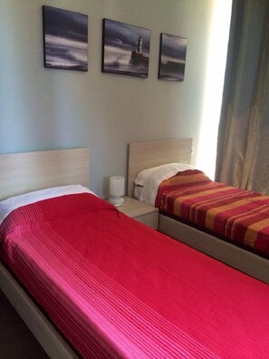 A hotel room with two beds, a nightstand, and three framed pictures on the wall. - My Room Roma (Rome)