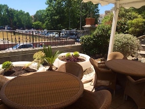 A terrace with wicker furniture and potted plants, overlooking a parking area and trees. - My Room Roma (Rome)