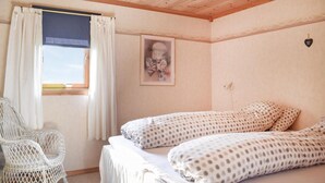 Une chambre avec deux lits, une fenêtre avec des rideaux, une chaise et un luminaire fixé au mur.