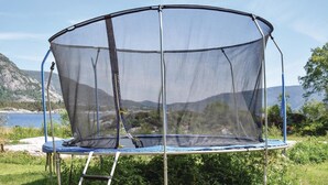 Un trampoline doté d’un filet de sécurité, installé à l’extérieur.