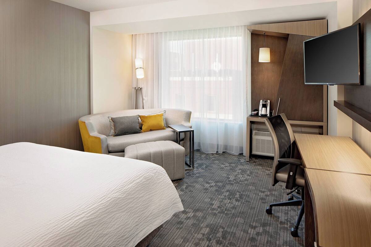 Une chambre d’hôtel avec un grand lit, un canapé, un bureau et une télévision.
