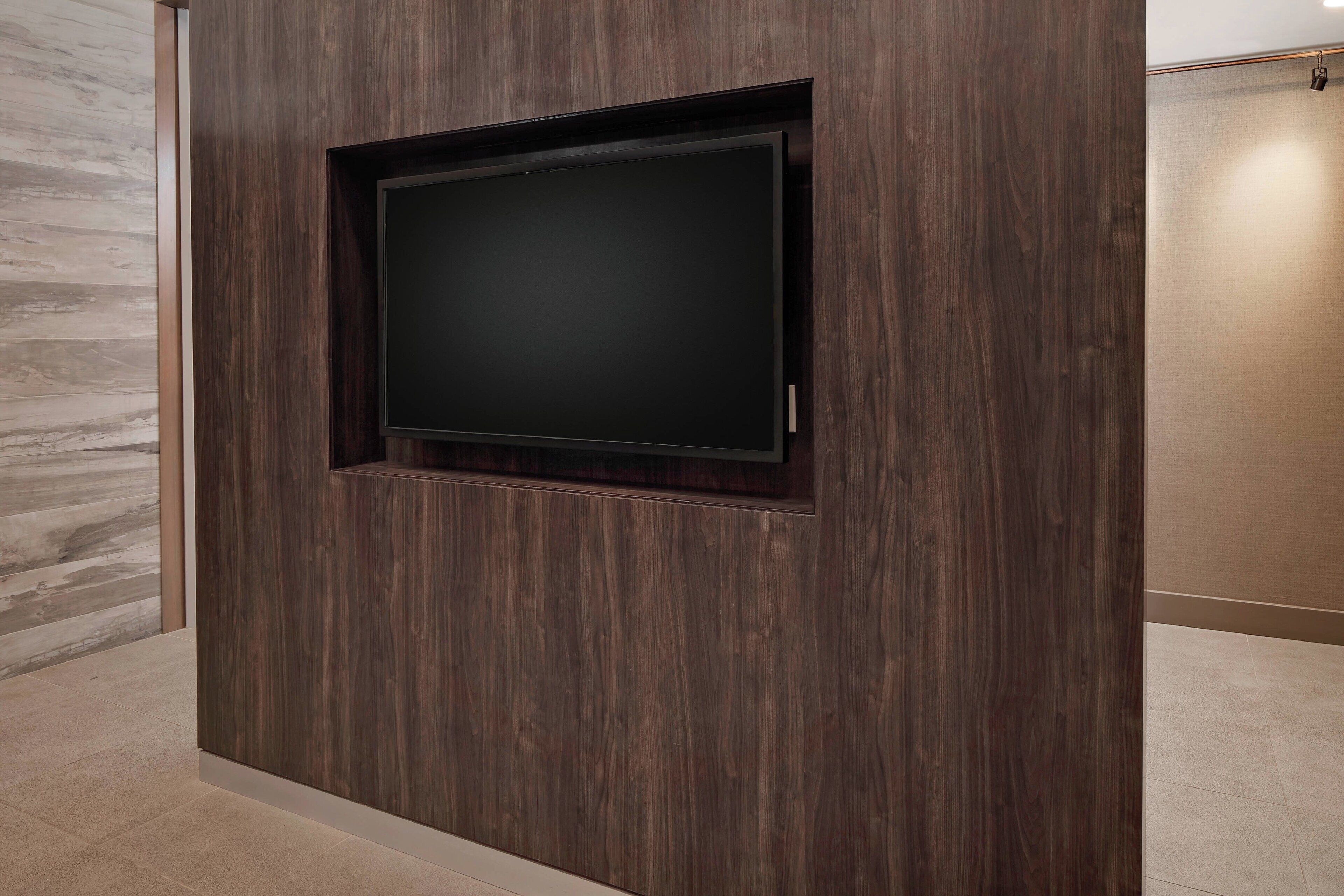 A dark wood-paneled wall with a recessed TV screen.