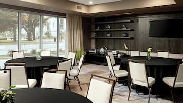 A conference room with a large table, chairs, a TV, and shelves with decorative items.