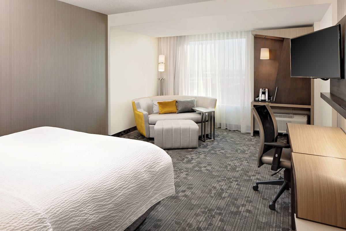 Une chambre d’hôtel comprenant un lit, un bureau, une chaise, un canapé et un téléviseur.