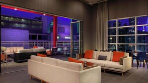 A modern living room with a sofa set, a dining area, and a large window with a city view. - Courtyard by Marriott Dallas Downtown/Reunion District (Dallas)
