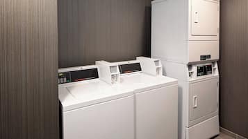 A laundry area with stacked washers and dryers, control panels, and a water dispenser.