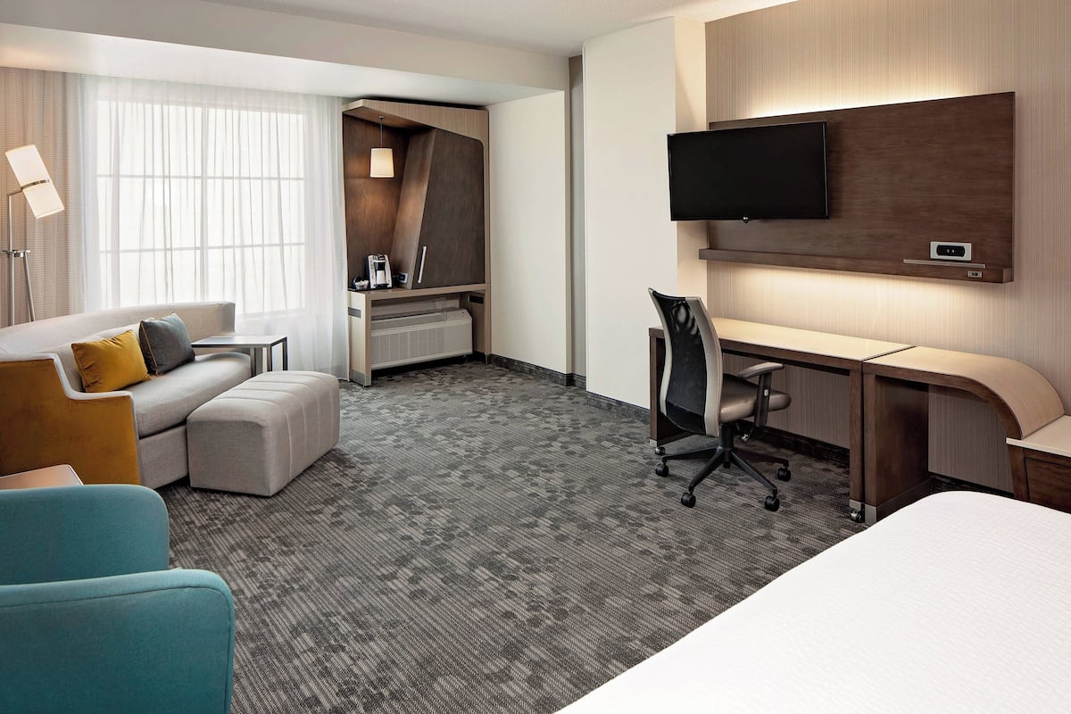 Une chambre d’hôtel équipée d’un lit, d’un bureau, d’une chaise, d’un canapé et d’une télévision.
