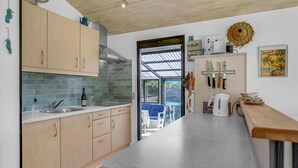 A kitchen with light wooden cabinets, a granite countertop, and a view of the outdoors through a glass door.