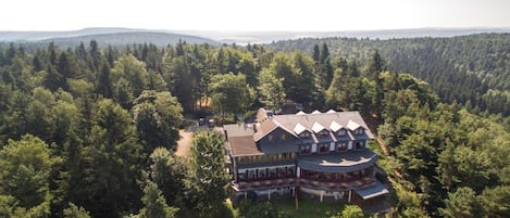 A large, multi-story building surrounded by dense forest, likely a lodge or resort.