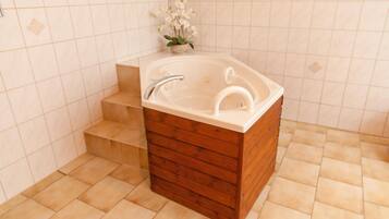 A bathroom with a freestanding bathtub, wooden cabinetry, and a small step leading to the tub.
