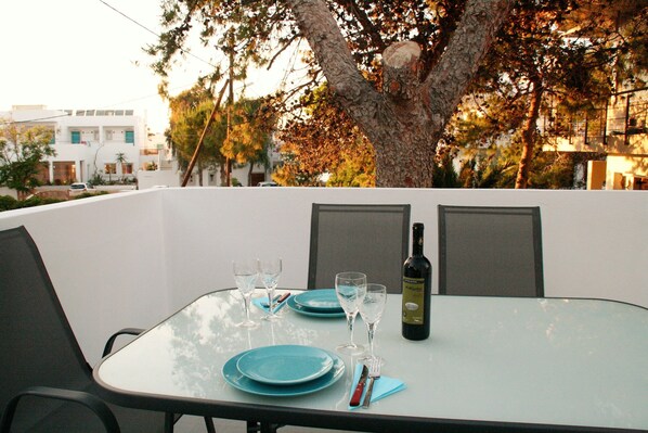 A table set for two with blue plates, wine glasses, and a bottle of wine. - Orama II (Chania)