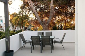 A terrace with a table and chairs, a potted plant, and a tree in the background. - Orama II (Chania)