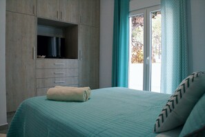 A bedroom with a bed, a built-in TV, a window with curtains, and a view of the outdoors. - Orama II (Chania)