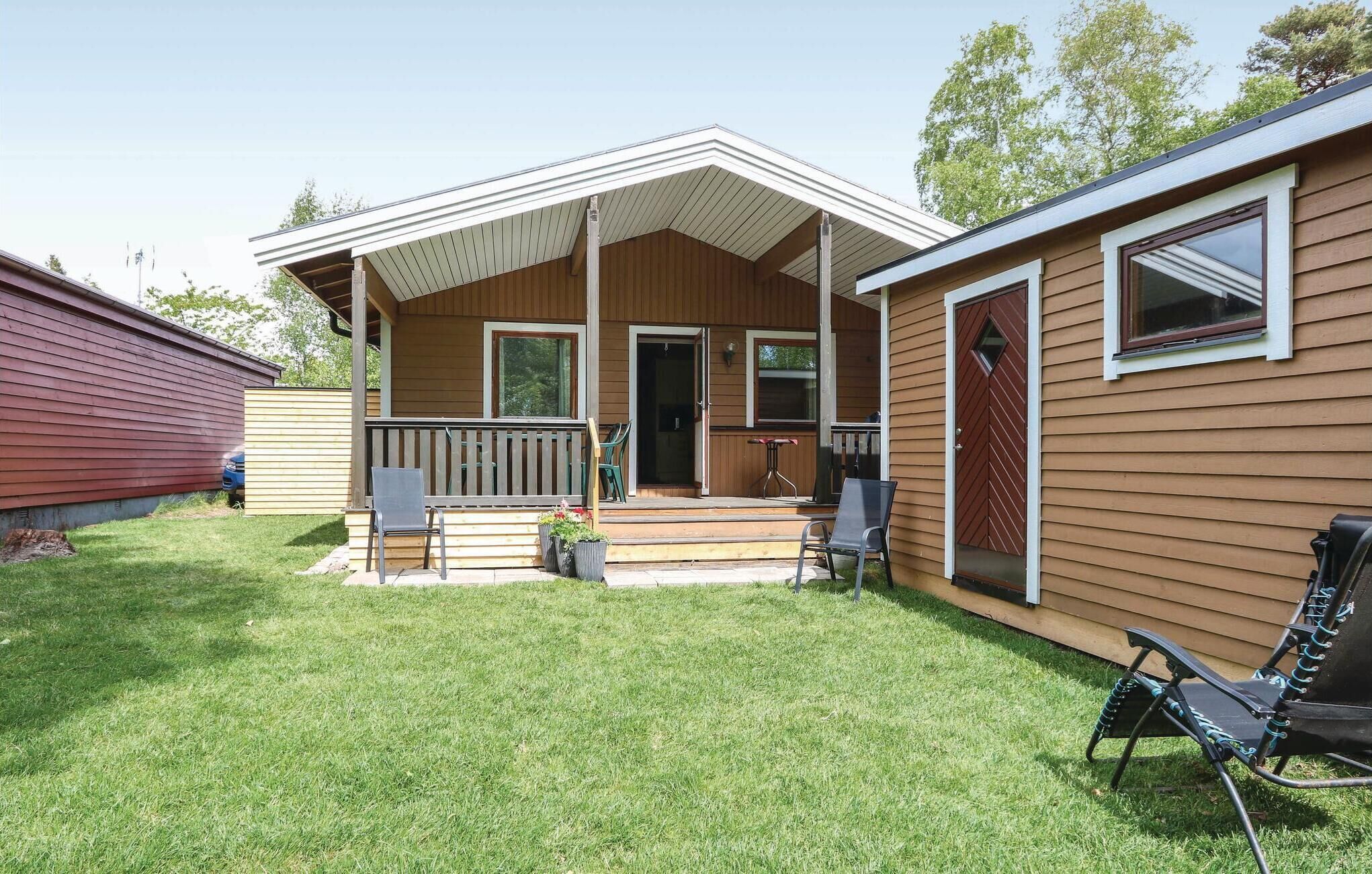 Een huis met twee verdiepingen, een overdekte veranda, een klein terras en een gazon.