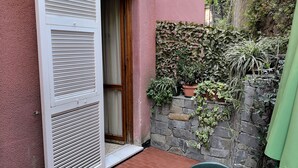 A small patio with a stone wall, potted plants, and a green chair. - Albergo Al Carugio (Monterosso al Mare)