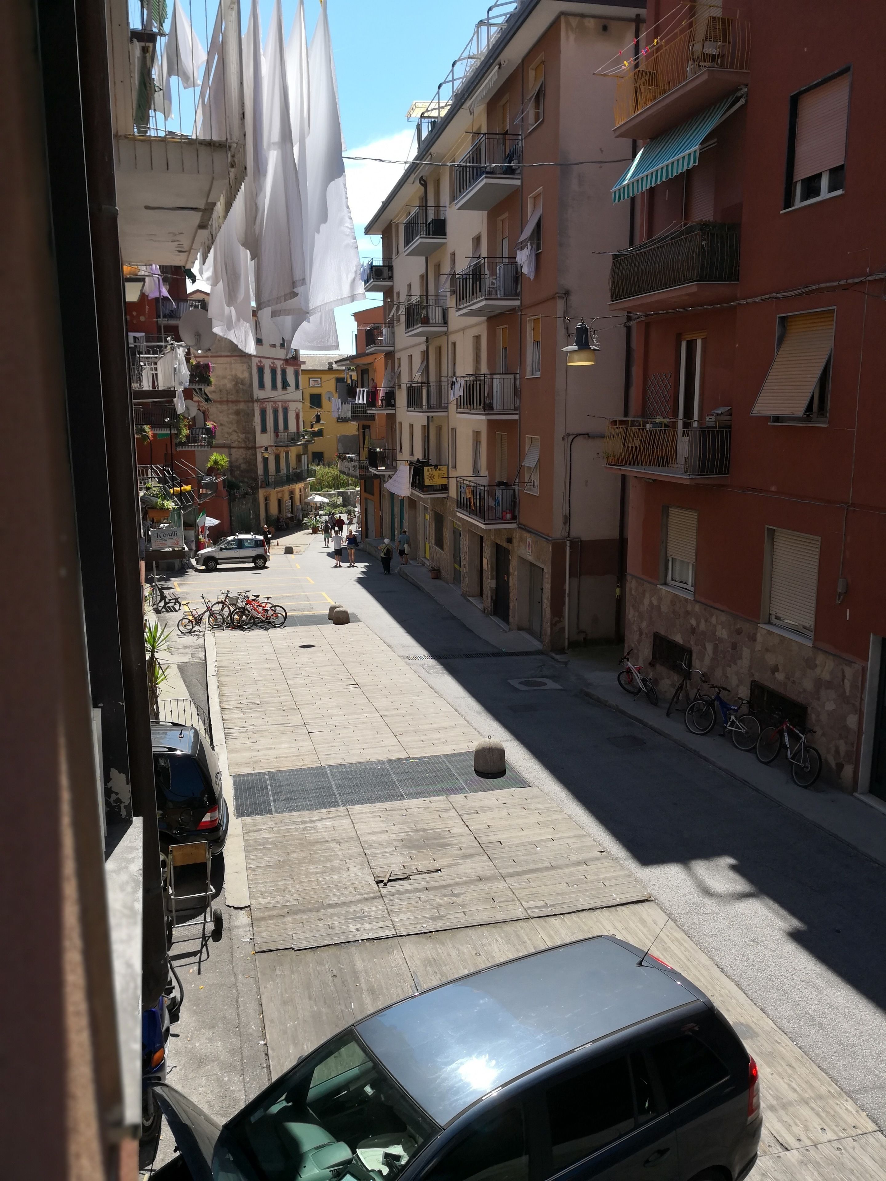 Eine schmale Straße gesäumt von mehrstöckigen Gebäuden, von denen einige Balkone und Außenplätze haben.