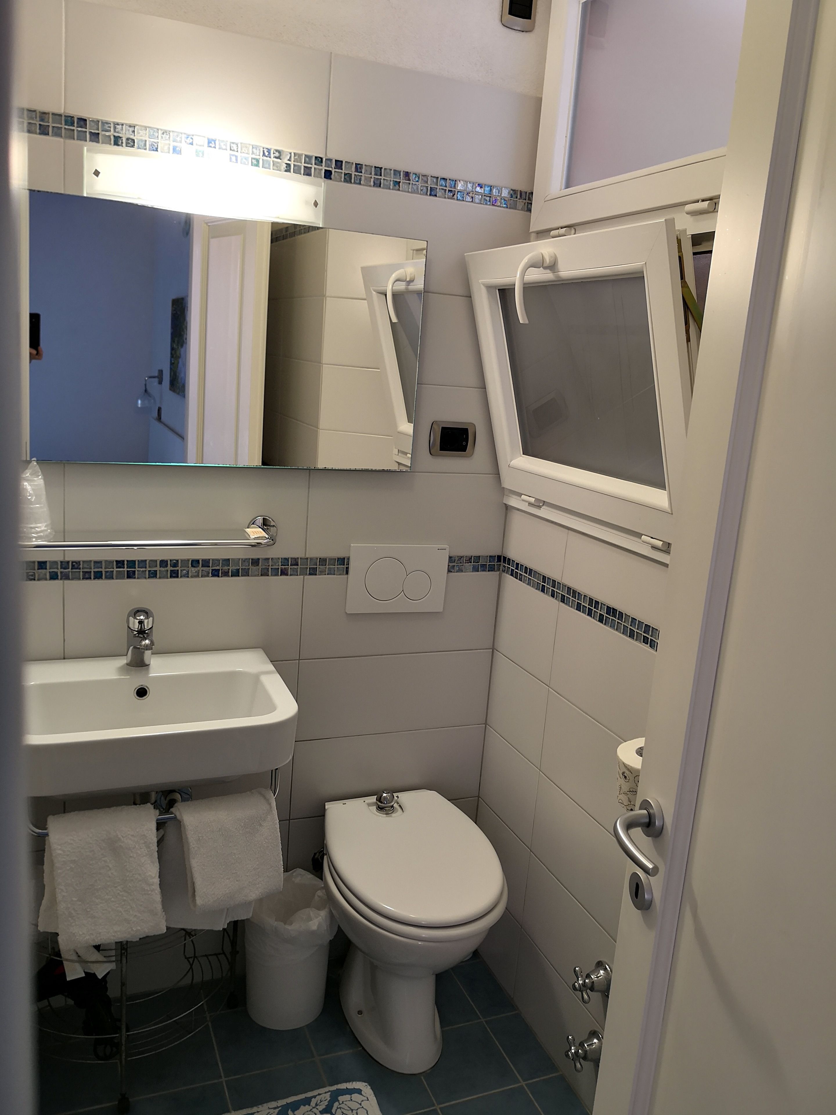 Un baño pequeño con lavamanos, inodoro y una ventana.