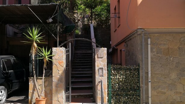A narrow street with a staircase leading to a building entrance, a parked car, and a potted plant. - Albergo Al Carugio (Monterosso al Mare)