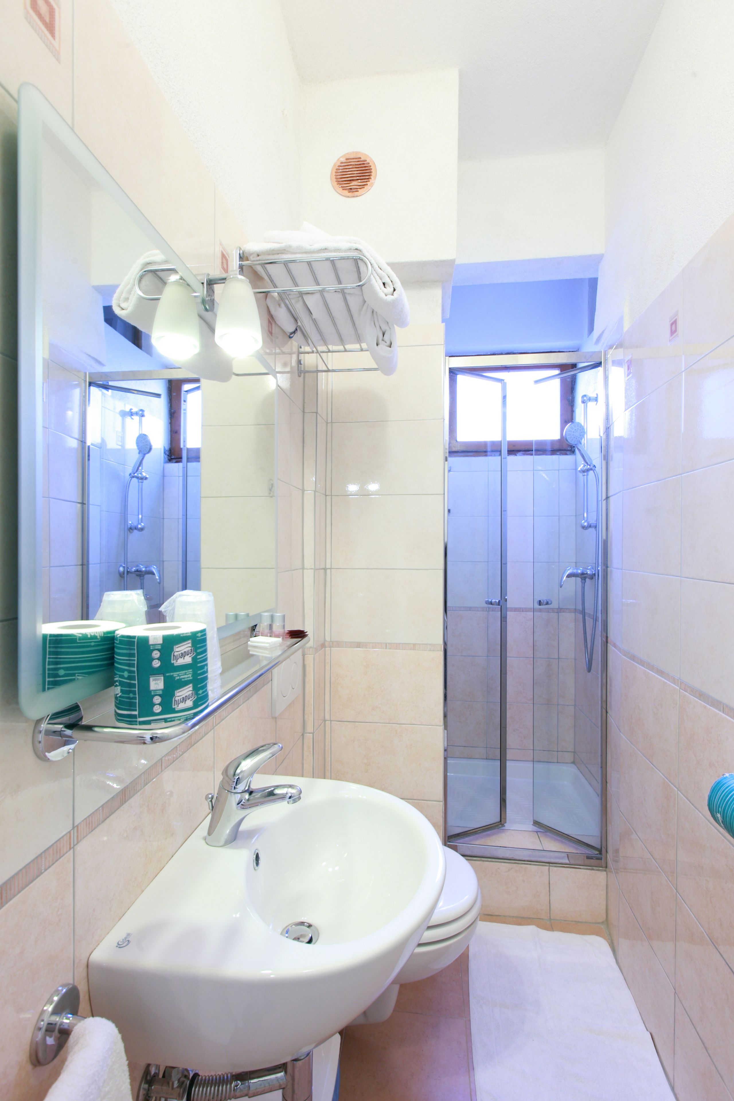 A bathroom with a sink, mirror, and shower.