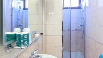 A bathroom with a sink, mirror, and shower.