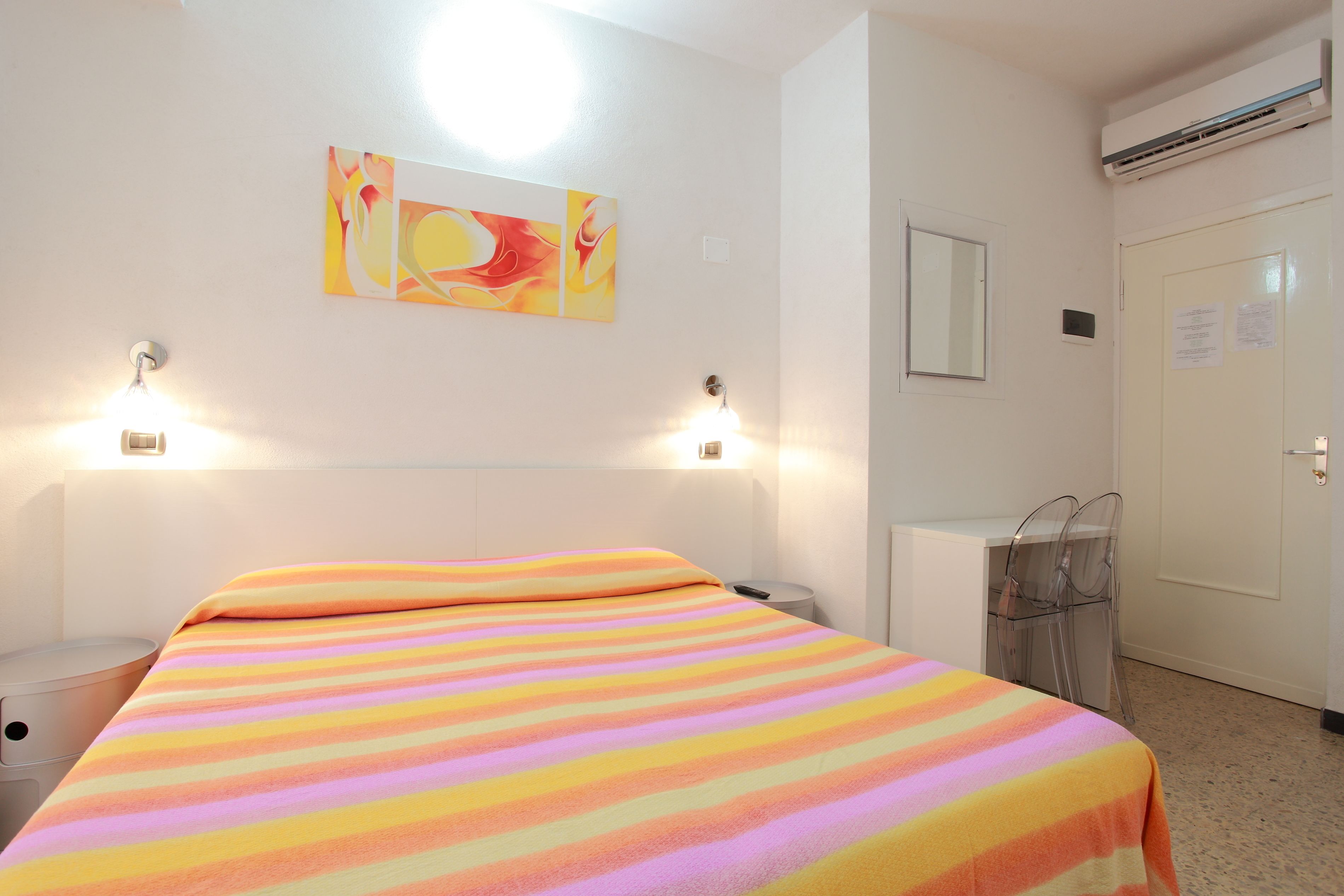 Une chambre d’hôtel avec un lit, des lampes de chevet, un bureau et une chaise.