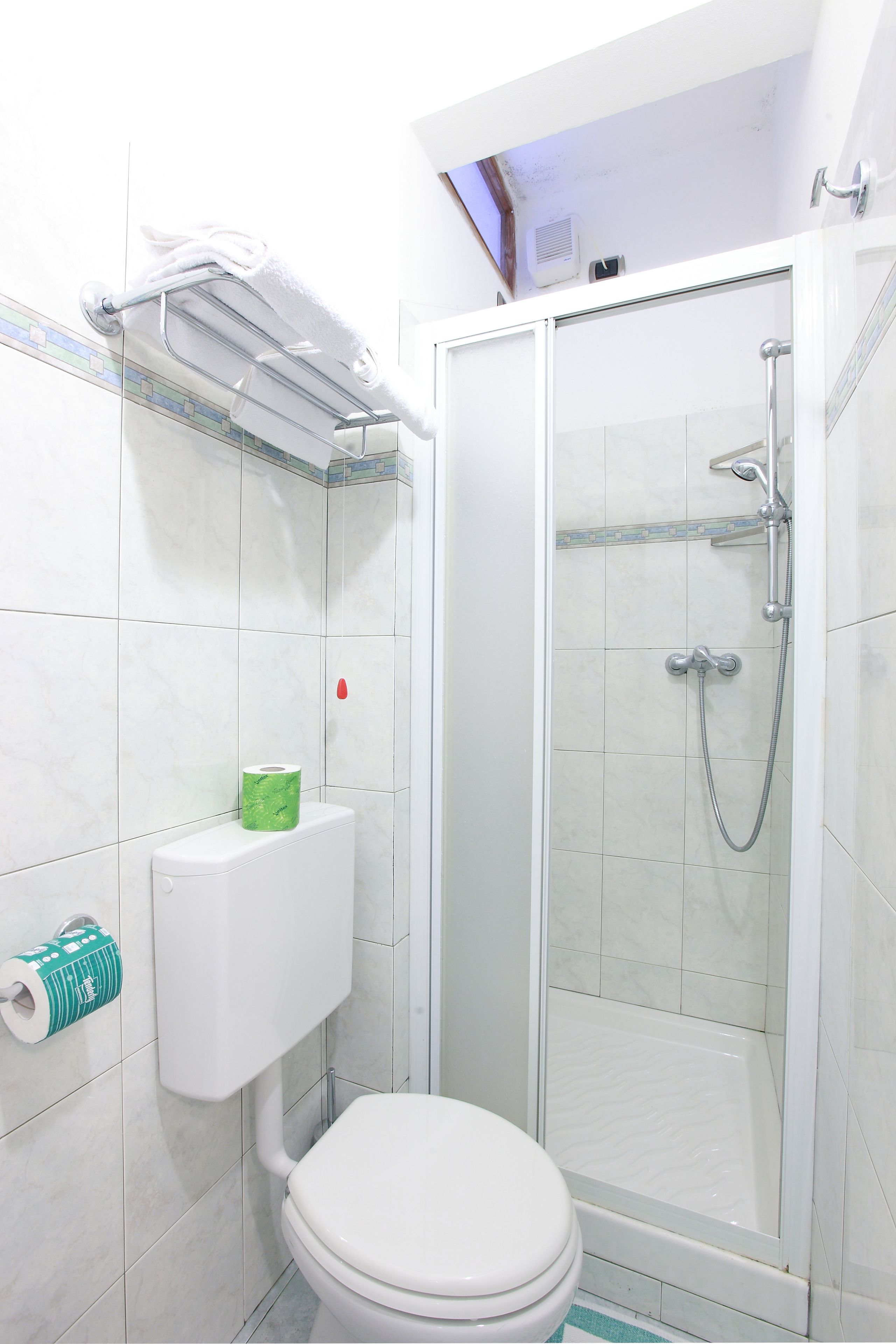 Un baño con inodoro, ducha y cabina de ducha con paredes de vidrio.