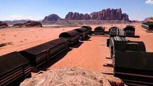 A desert landscape with stacks of black luggage in the foreground and rocky mountains in the background. - Wadi Rum Protected Area Camp (Wadi Rum)