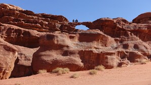 A natural rock formation with two people standing on a narrow ledge. - Wadi Rum Protected Area Camp (Wadi Rum)