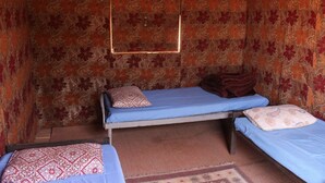 A small, cozy room with two single beds, a mirror, and patterned wallpaper. - Wadi Rum Protected Area Camp (Wadi Rum)