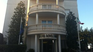 A hotel with a central balcony, columns, and a flag. - Hotel Sovrano (Alberobello)