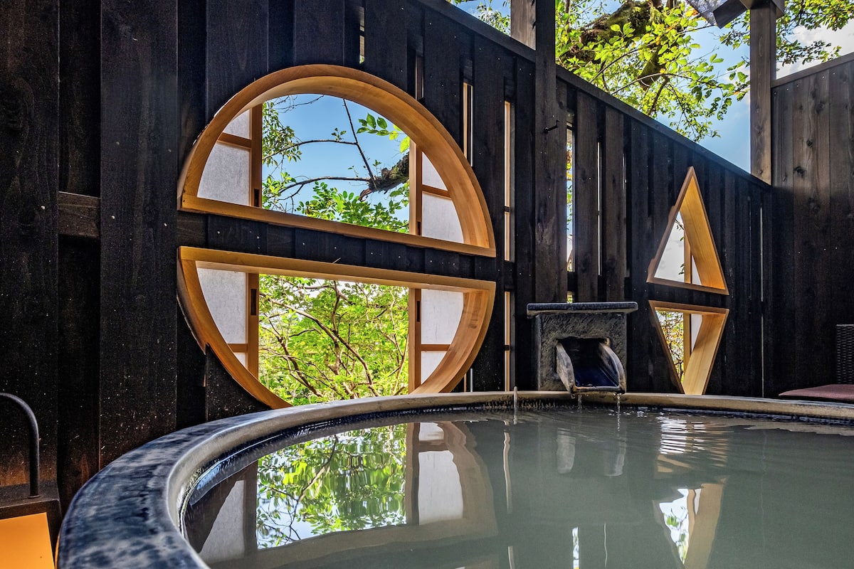 Un área de spa con bañera de hidromasaje, paredes de madera y ventanas amplias.