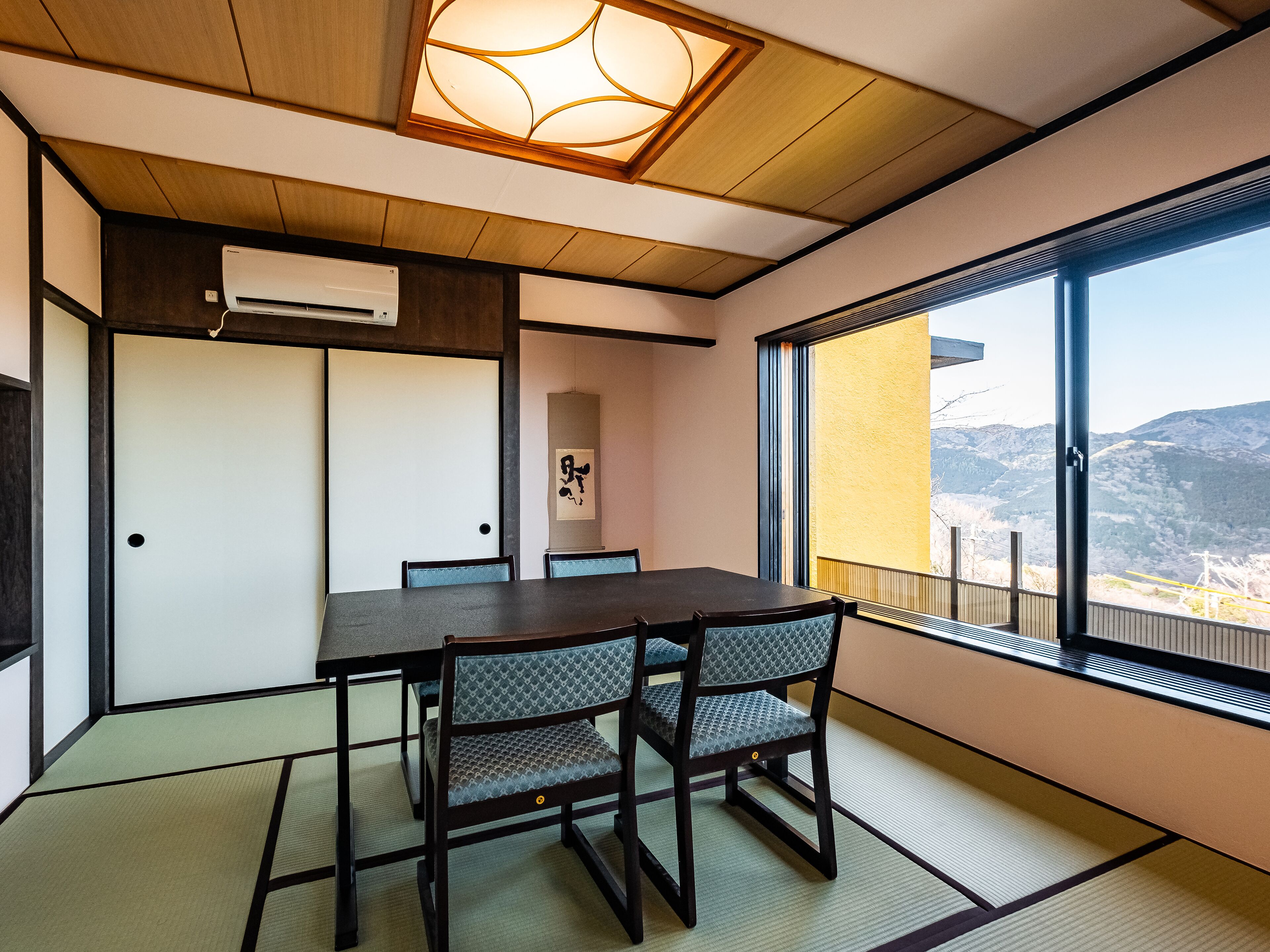 A traditional Japanese-style room with tatami flooring, a low table, and chairs.