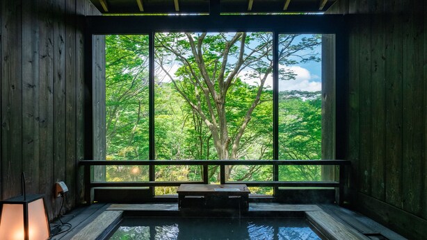 Un spa de madera con una ventana grande, una fuente termal y una banca.