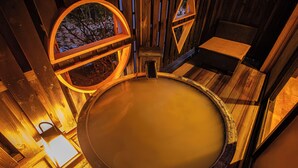 Una sauna de madera con un jacuzzi circular, bancos de madera y una pared de madera con ventana.