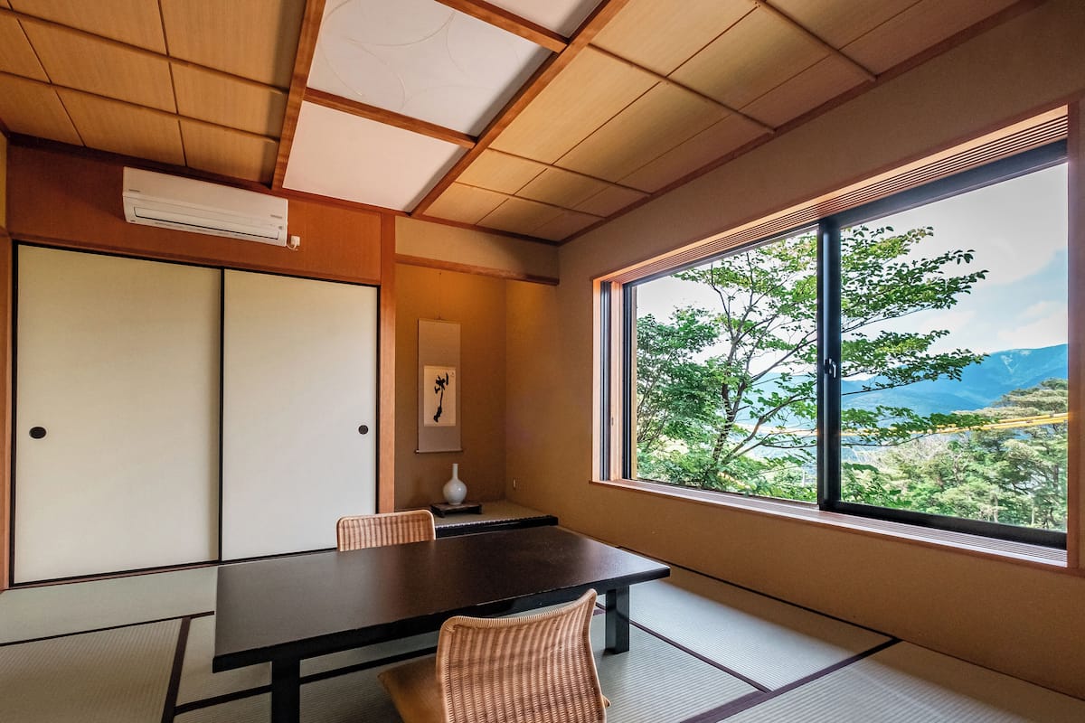 Una habitación japonesa tradicional con suelo de tatami, una mesa baja y puertas correderas.