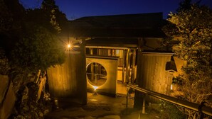 Una estructura de madera con un ventanal circular y un farol en el suelo.