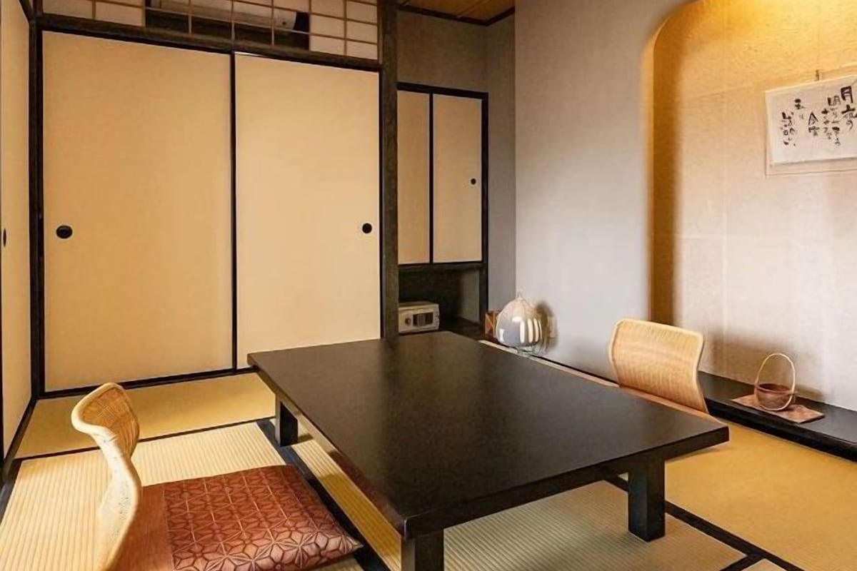 Una habitación japonesa tradicional con suelo de tatami, una mesa baja y paneles shoji.