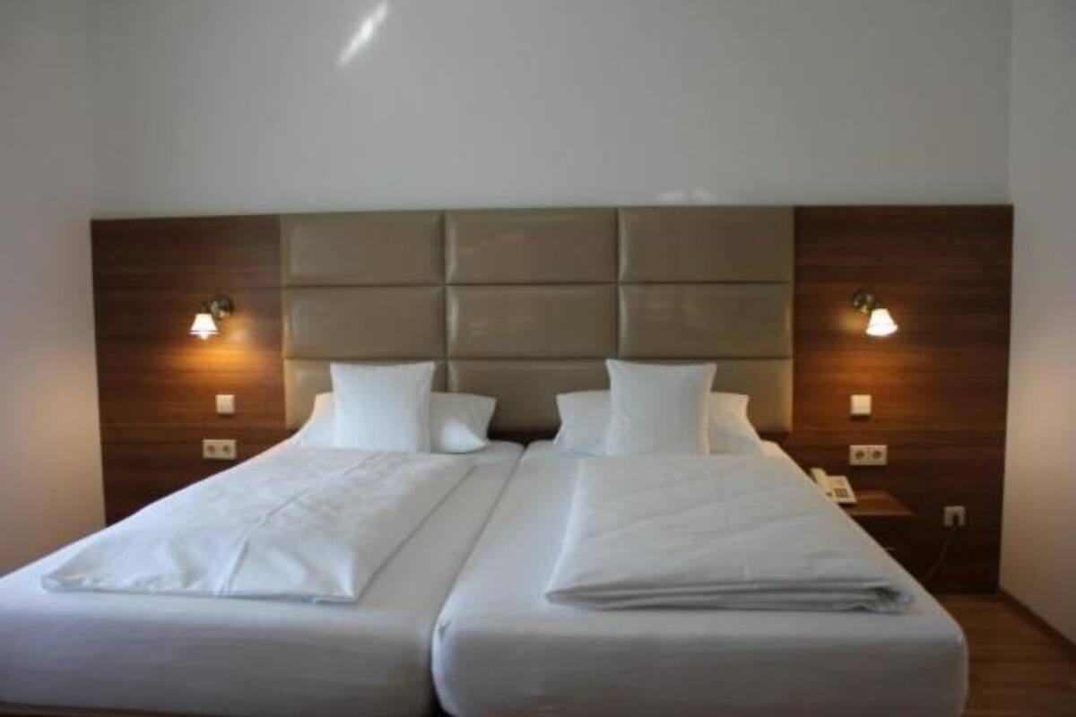 A double bed with a padded headboard, two bedside tables with lamps, and a neutral color scheme.