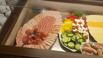 Un buffet con diverse pietanze, tra cui salumi, formaggi, verdure e salsicce.