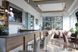 A modern bar area with wooden counter, bar stools, and pendant lighting. - Hotel Rheinbrücke (Rheinfelden (Baden))