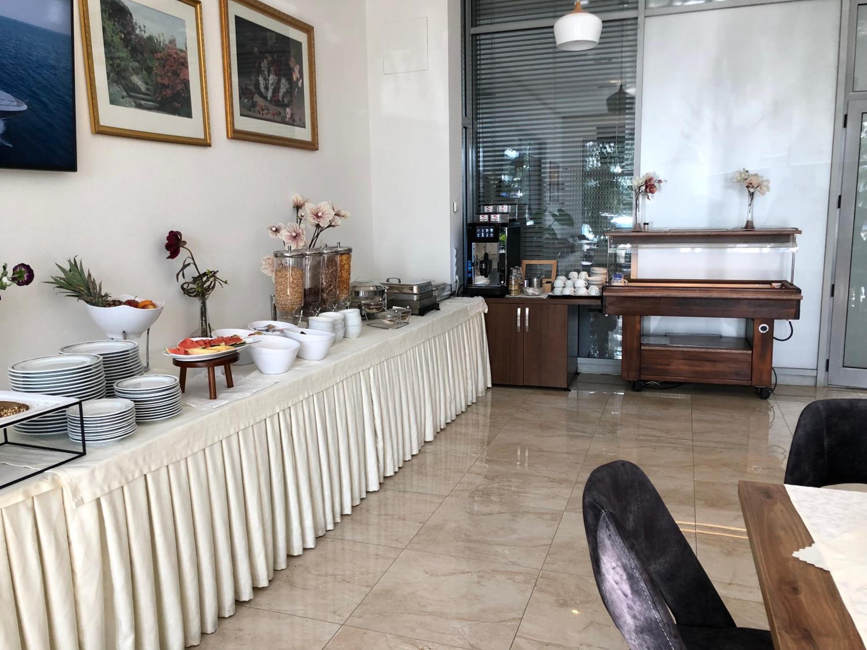 A dining area with a buffet setup, including plates, bowls, and a coffee station.