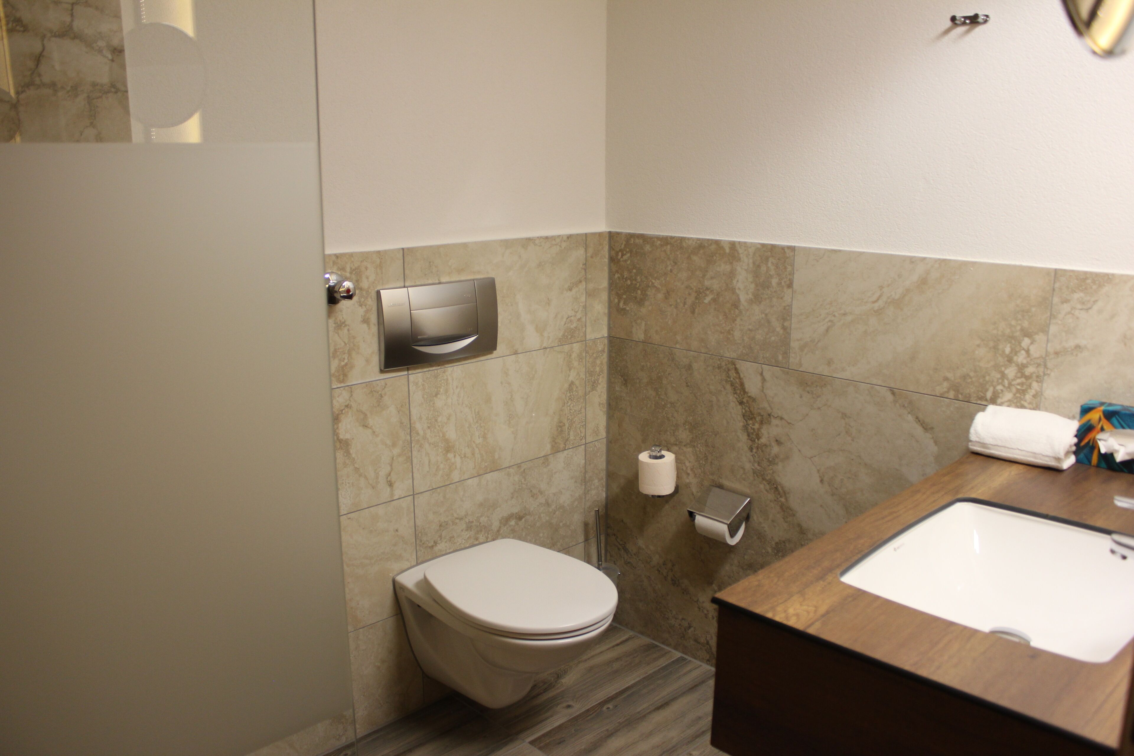 Une salle de bain équipée d’un WC, d’un lavabo, d’un distributeur de serviettes et d’un distributeur d’essuie-tout.