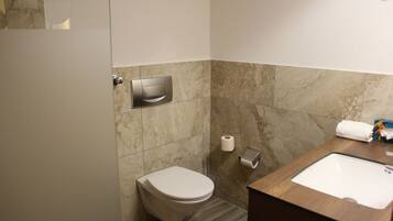 Une salle de bain équipée d’un WC, d’un lavabo, d’un distributeur de serviettes et d’un distributeur d’essuie-tout.