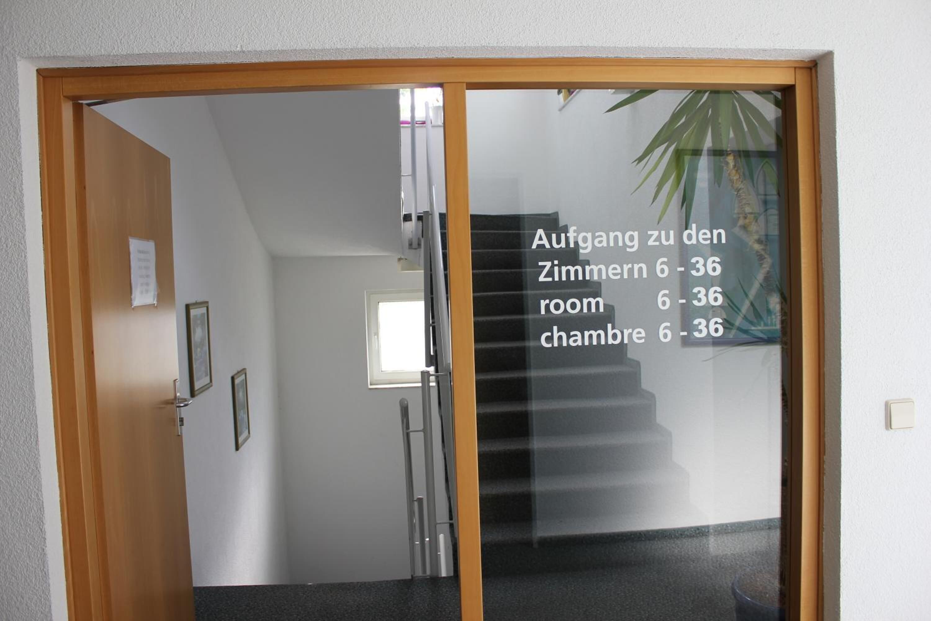 Una habitación con una puerta que da a una escalera. Texto en la puerta indica los números de habitación 6 al 36.