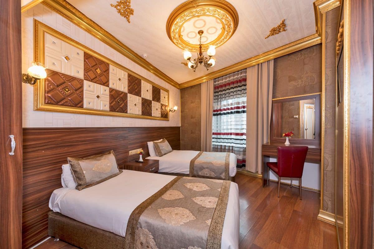 A hotel room with two beds, a desk, and a mirror.