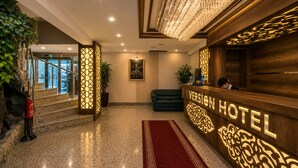 A hotel reception area with a reception desk, a red carpet, and a chandelier. - Version Hotel (Istanbul)