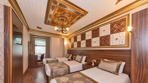 A hotel room with three beds, a chandelier, a large decorative ceiling, and a checkered wall panel. - Version Hotel (Istanbul)