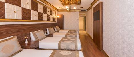 A hotel room with a long corridor leading to a door, a chandelier, and a patterned wall.