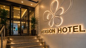 A hotel entrance with a modern sign, a staircase, and potted plants. - Version Hotel (Istanbul)
