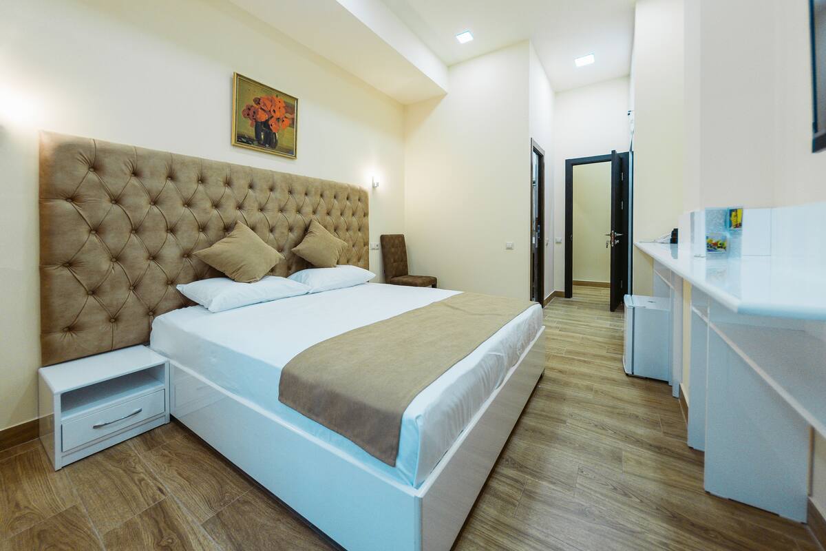 Ein ordentlich eingerichtetes Schlafzimmer mit einem großen Bett, Nachttischen und einem kleinen Schreibtisch.